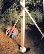 a man kneeling down next to a pole on the side of a hill with trees in the background