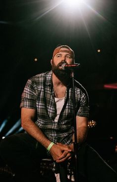 a man with a beard sitting in front of a microphone and singing into a microphone