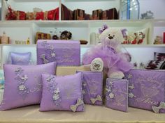 a teddy bear sitting on top of purple pillows next to other decorative items in a store