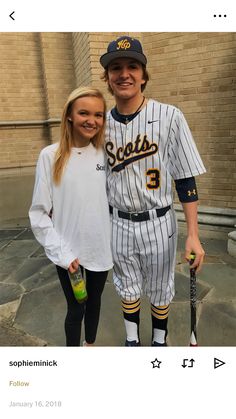 two people standing next to each other in baseball uniforms