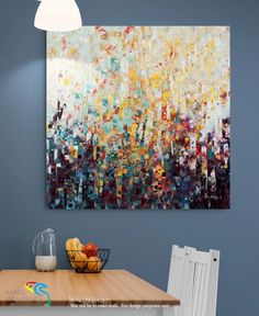 an abstract painting hangs on the wall above a table with fruit and milk in front of it