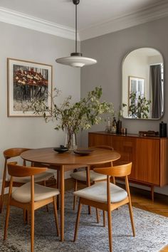 a dining room table with four chairs and a mirror on the wall in front of it