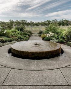 a water fountain in the middle of a garden with steps leading up to it's entrance