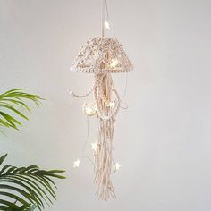 a white chandelier hanging from the ceiling next to a potted plant on a table