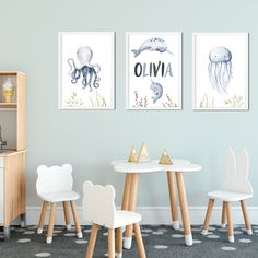 three children's artwork prints on the wall above a table and chairs in a playroom