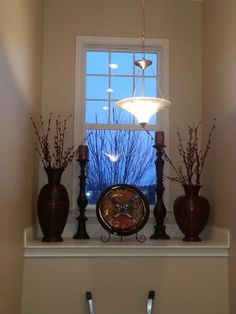 a clock sitting on top of a shelf next to two vases