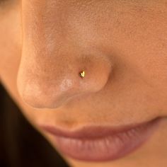 a woman's nose with a tiny yellow stud in the middle of her nose