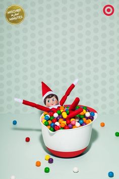 an elf is sitting in a bowl filled with candy