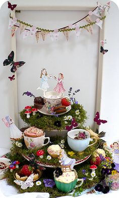 there is a tea party set up in the shape of a tree with fairy figurines on it