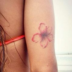 a close up of a person's arm with a flower tattoo on her left side