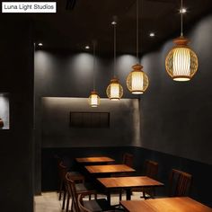 an empty dining room with wooden tables and chairs, hanging lights over the table in front of them