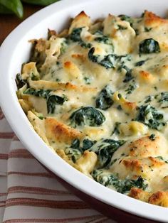 a casserole dish with spinach and cheese in it on a striped cloth