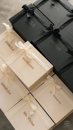 four black boxes with white ribbons and bows on them are sitting next to each other