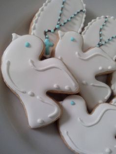 decorated cookies in the shape of doves on a white plate with blue beaded necklaces