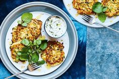 two plates filled with food on top of a blue table cloth next to silverware