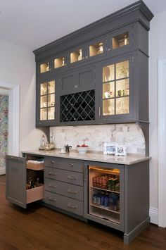 a kitchen with gray cabinets and white marble counter tops, wood flooring and hard wood floors