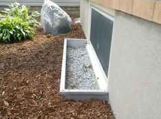 a rock sits in the middle of a garden bed next to a building with a window