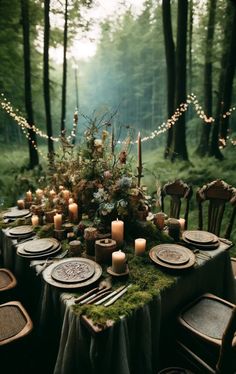 a table set with candles and plates in the woods