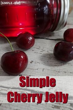 a jar filled with cherries sitting on top of a white wooden table next to two cherries