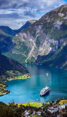 a cruise ship is docked in the water near mountains and houses on either side of it