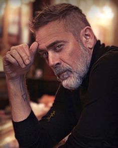 a man with a grey beard and tattoos on his arm is looking at the camera