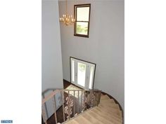 a staircase with a mirror on the top and chandelier above it, in front of a window