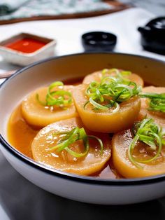 a bowl filled with cooked food and garnished with scallions on top