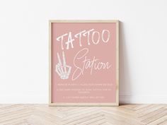 a pink poster with the words tattoo station written in white on it next to a wooden floor