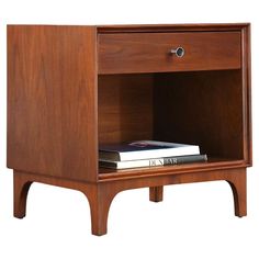 a wooden nightstand with two books on top and one drawer open to reveal a book