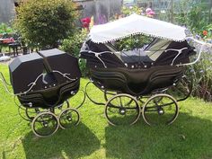 two baby carriages sitting in the grass under an umbrella