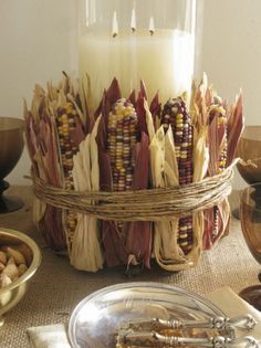 an arrangement of corn on the cob with a lit candle and other food items