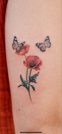 a woman's arm with three flowers and two butterflies on the back of her shoulder