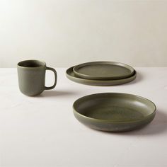 three plates and two cups sitting on a table top with one empty plate in the middle