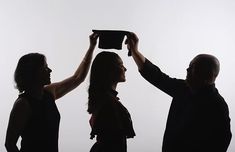 three people holding up a black object in the air