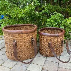 two large wicker baskets sitting on top of a stone floor next to green bushes