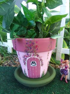 a potted plant sitting on top of a green plate next to a small figurine