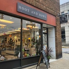 a store front with lots of potted plants in it's windows and the words hoot and how written on the window