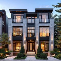 a large modern house with lots of windows and plants in front of the entrance to it