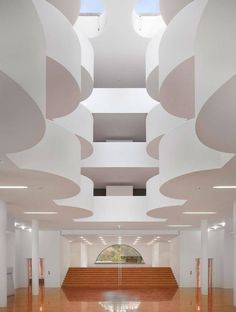 the inside of a building with wooden floors and white walls, an open staircase leads up to a skylight