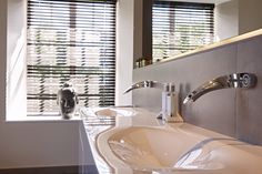 there is a sink in the bathroom with two faucets and a window behind it