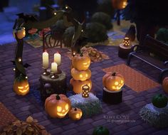 pumpkins are lit up on the ground in front of a bench and tree with candles