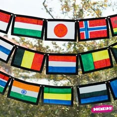 colorful flags hanging from a string in front of a tree