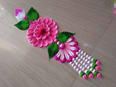 some flowers are laying on the floor with green leaves and pink flowers next to it