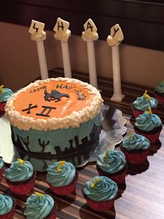 a birthday cake with candles and cupcakes on a table