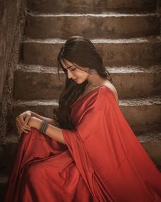 a woman in a red dress sitting on some steps