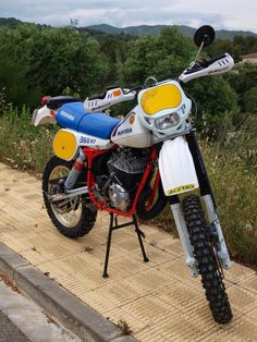 a dirt bike parked on the side of a road next to some grass and trees