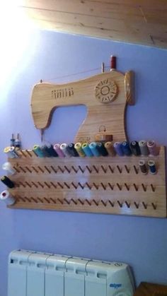 a wall mounted sewing machine on a wooden rack with spools of thread hanging from it