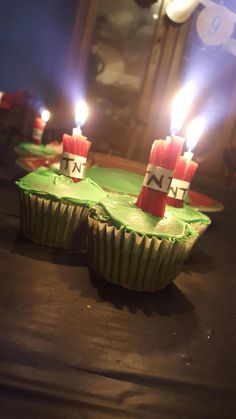 three cupcakes with lit candles sitting on a table