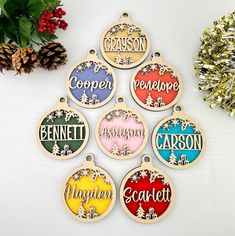 six personalized christmas ornament hanging on a white table next to pine cones