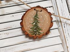 a wooden ornament with a pine tree on it's side hanging from a rope